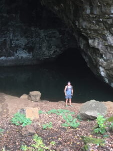 Matt Miller standing on the shore of a body of water inside a cave-like structure