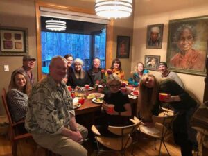 Photo of a group of people sitting around a table having a meal, smiling and looking at the camera