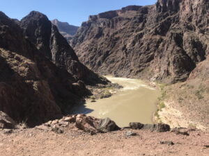View from a rocky cliff overlooking a small river running through dark rocky cliffs