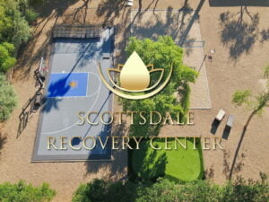Overhead photo of a sports complex featuring a basketball court, sandy volleyball court, and golf course, with a logo of Scottsdale Recovery Center