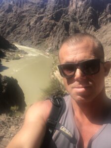 Selfie of Matt Miller in front of a small river and a steep cliff