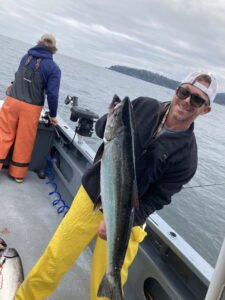 Matt Miller on a boat on a large water body holding a large fish he caught