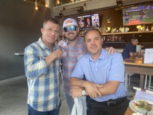 Matt Miller in a photograph with two friends, in a restaurant or pub setting
